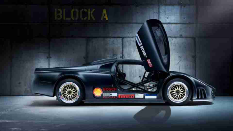 El auto concepto Volkswagen W12 Nardo 2001 estacionado en un cuarto oscuro con las puertas de mariposa abiertas, mostrando una vista lateral del vehículo.