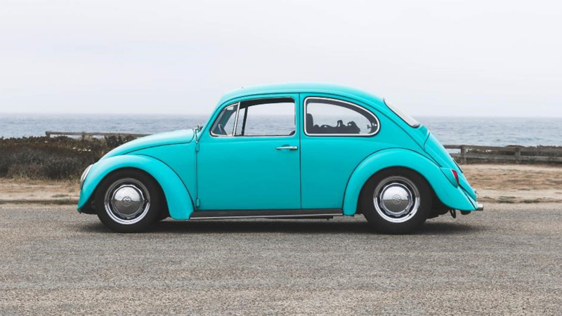 Un Volkswagen Beetle vintage estacionado frente al océano