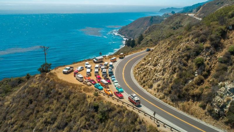 Vintage Volkswagen vehicles at an overlook by the ocean