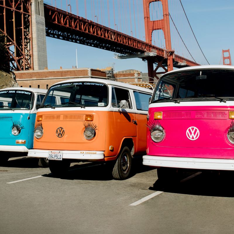 Cuatro autobuses Volkswagen vintage estacionados frente a un puente