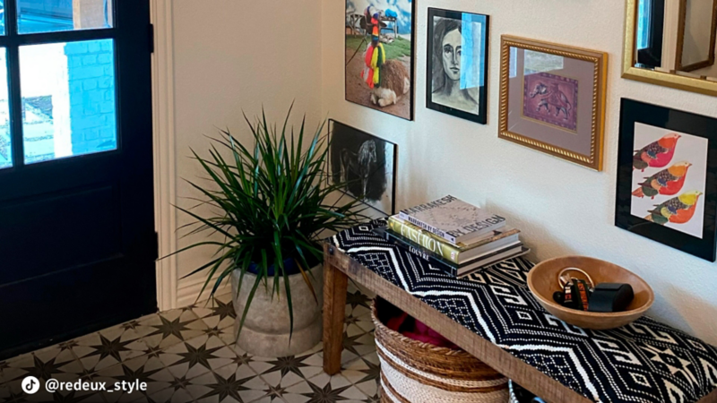 La entrada de una casa, con obras de arte enmarcadas y perchas en las paredes.