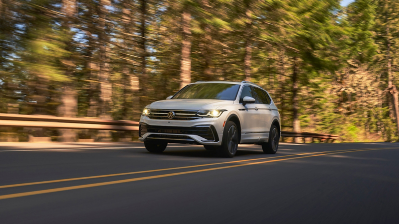 Front shot of a Tiguan in Oryx White driving on the road with trees in the background.