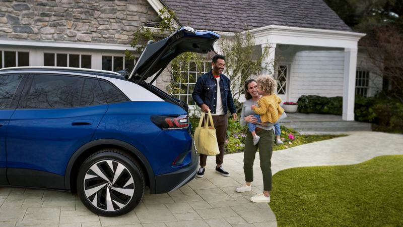 Una familia carga su Volkswagen ID.4 2021 frente a su casa. 