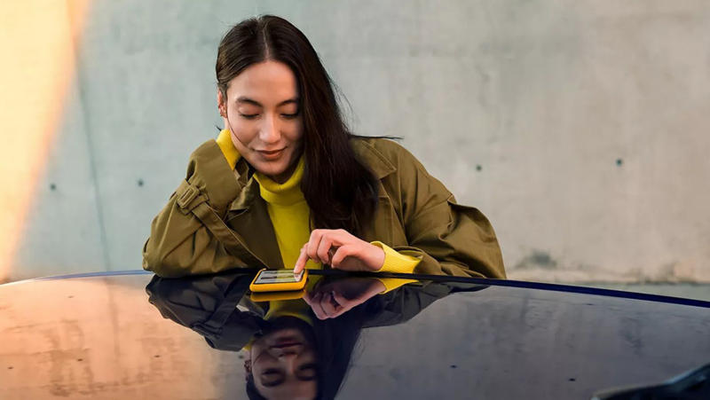 Woman looking information on her cellphone which is resting on a VW.