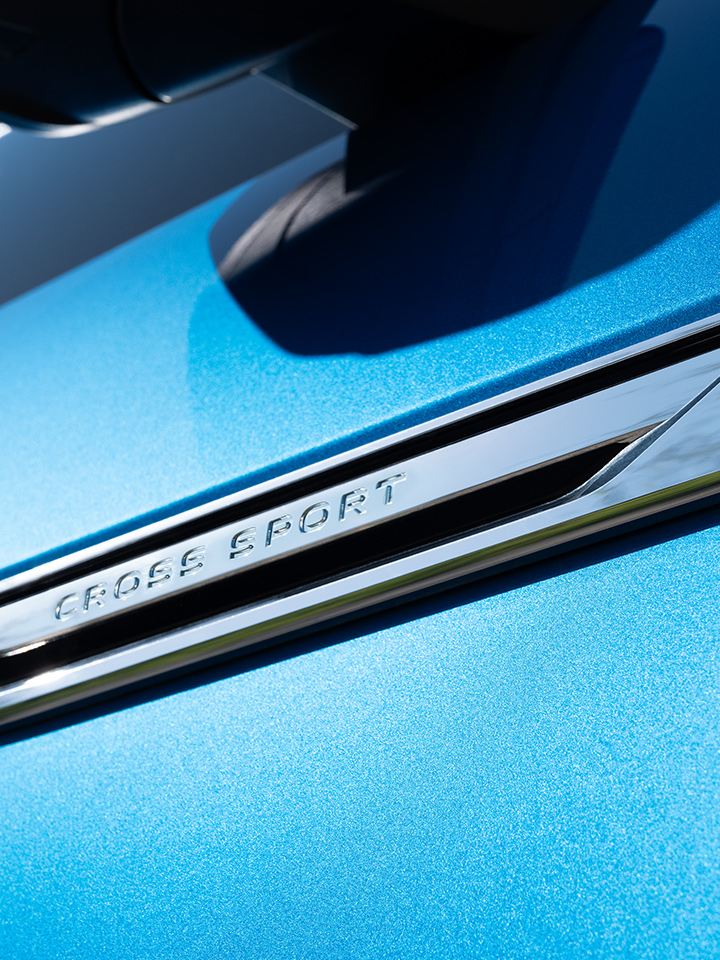 A close-up view of the exterior badging of an Atlas Cross Sport shown in Kingfisher Blue Metallic.