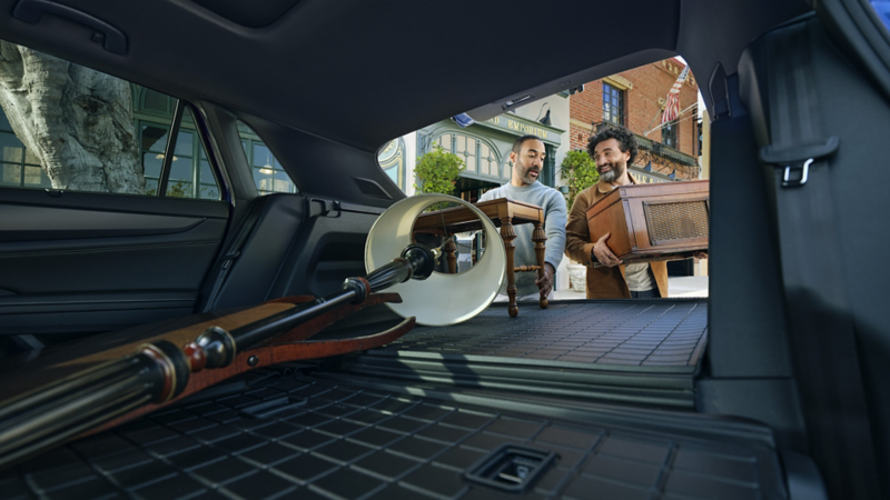 A view of a lamp in the cargo space of the Atlas Cross Sport with the rear seat down and a couple loading a table and record player.
