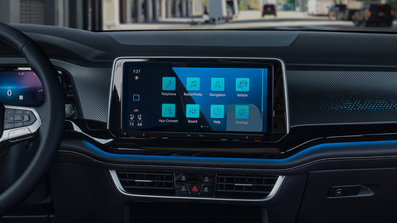 Close-up interior view of the center display on the front dash of the Atlas Cross Sport with city buildings in the background.