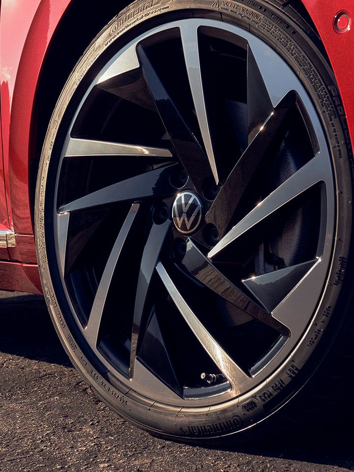 Close up of the available 20" alloy wheel on the front passenger side of an Arteon in Kings Red Metallic.