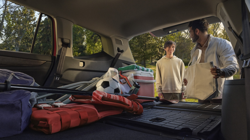 A father and son load sports equipment into the cargo area of an Atlas.