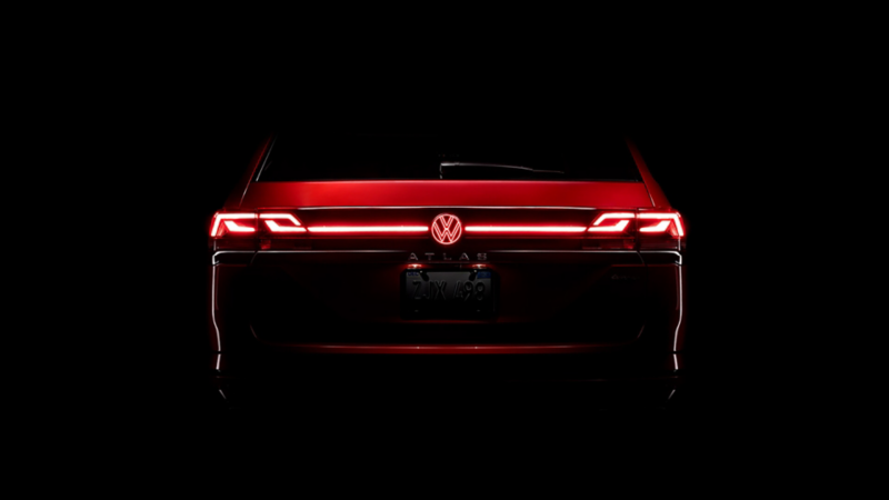 Rear of an Atlas in Aurora Red Metallic at night with available illuminated grille and rear VW emblem.