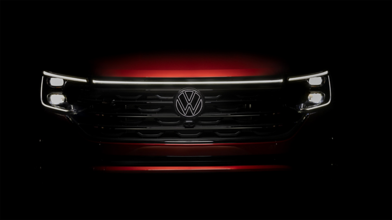 Front of an Atlas in Aurora Red Metallic at night with available illuminated grille and front VW emblem.