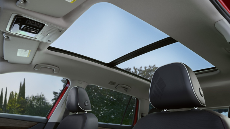Interior view of an Atlas looking up through the available panoramic sunroof with trees visible through the windows.