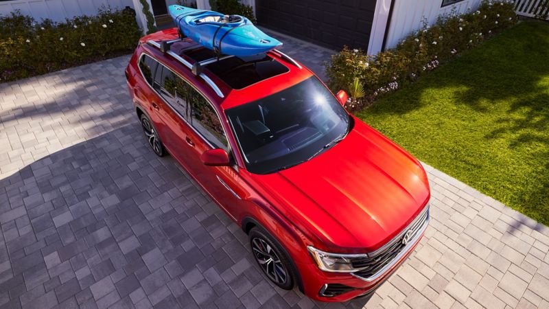 Overhead view of an Atlas shown in Aurora Red Metallic parked in a driveway with an accessory roof rack mounted kayak on the roof rails.