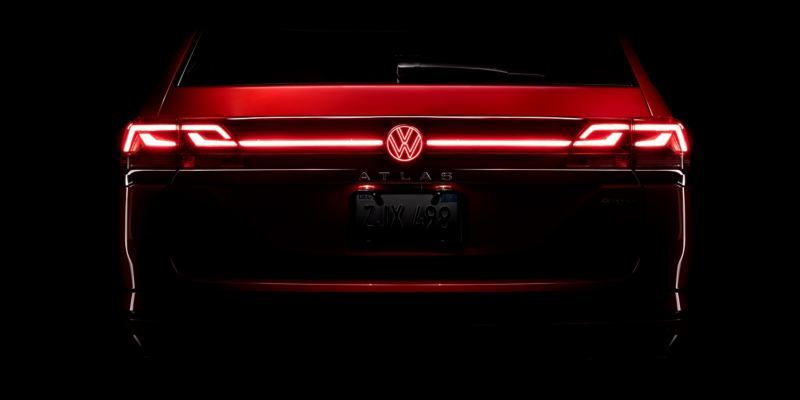 Rear of an Atlas in Aurora Red Metallic at night with available illuminated grille and rear VW emblem.