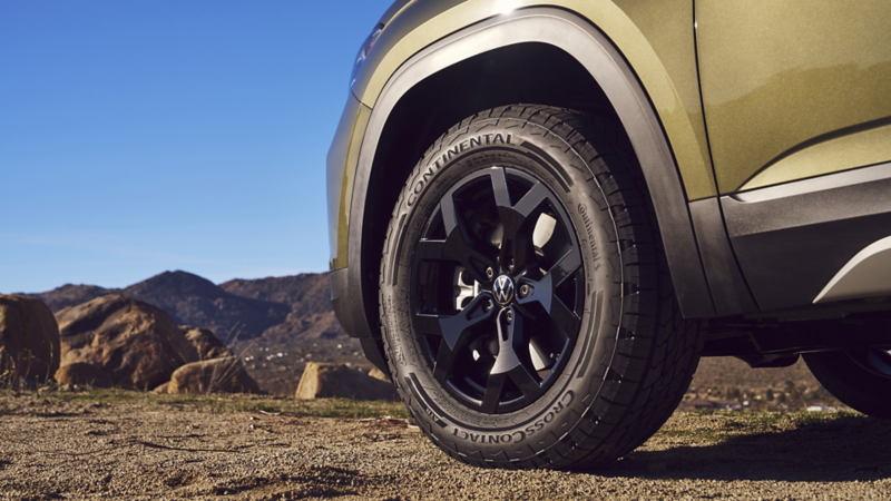 Available Black 18” alloy wheels shown on an Atlas in Avocado Green Metallic parked in a desert setting.