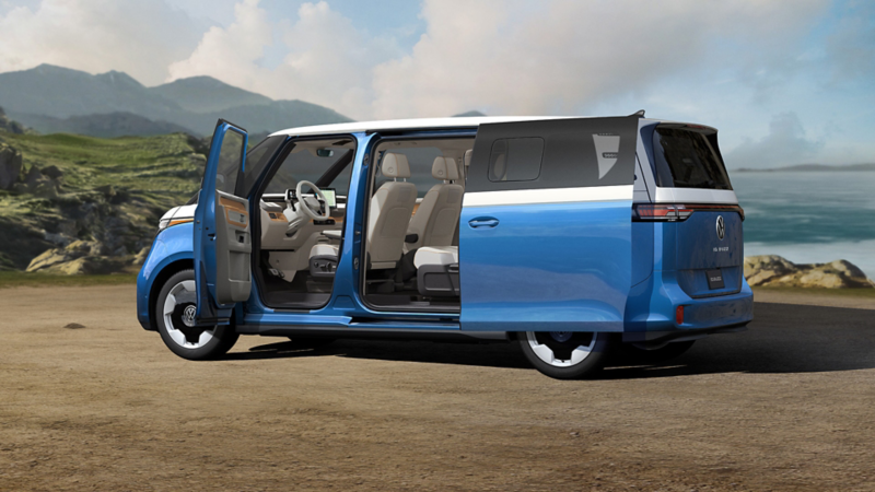 An ID. Buzz shown in Cabana Blue Metallic and Candy White with the front and side sliding doors open is parked with a beach and ocean in the background.
