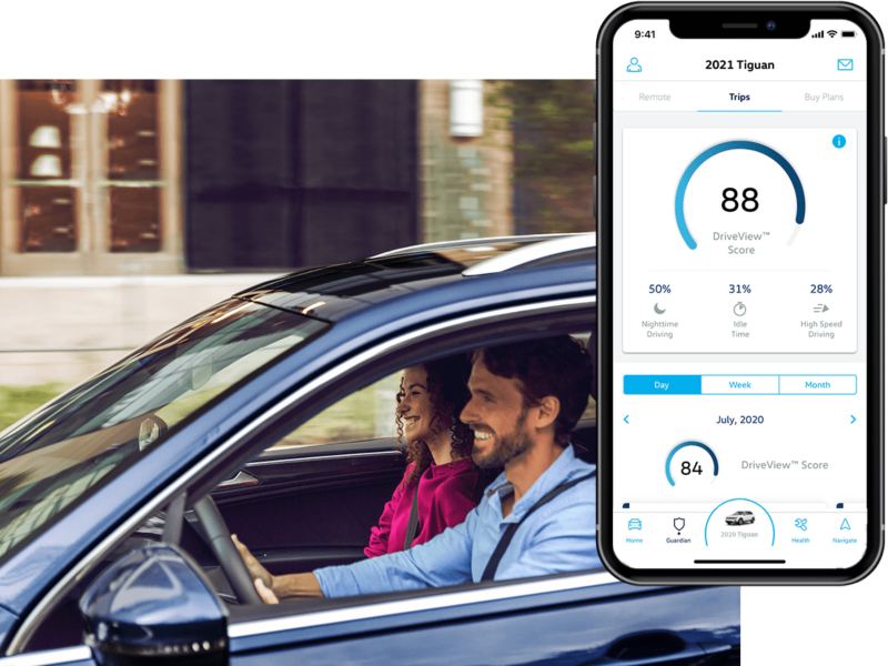 Un hombre conduce su VW; la aplicación VW Car-Net® Remote Access Drive View se muestra en un teléfono móvil superpuesto.