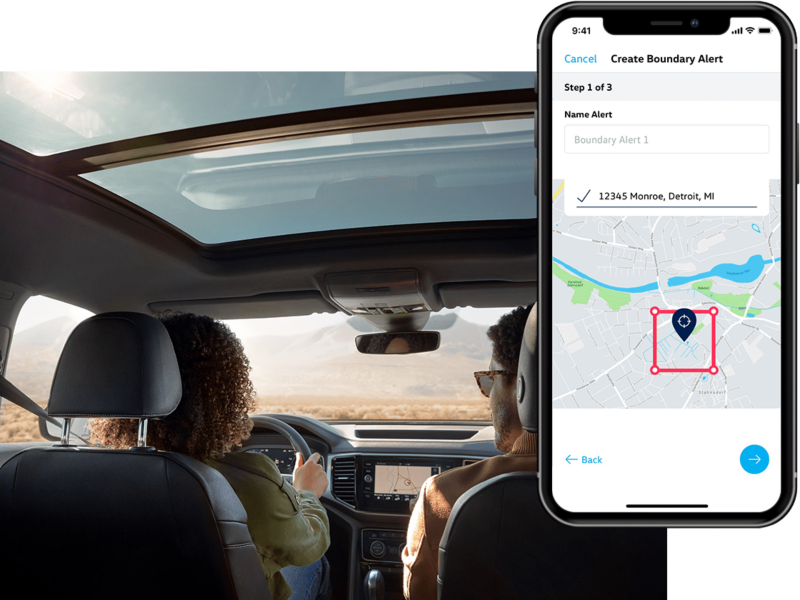 A man and woman review their Boundary Alert in their Car-Net app from their parked Volkswagen.