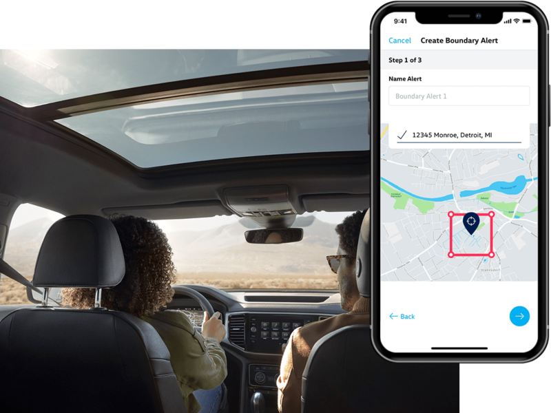 A man and woman sit in their VW with the in-app, VW Car-Net® Remote Access boundary parameter displayed on a superimposed mobile phone.
