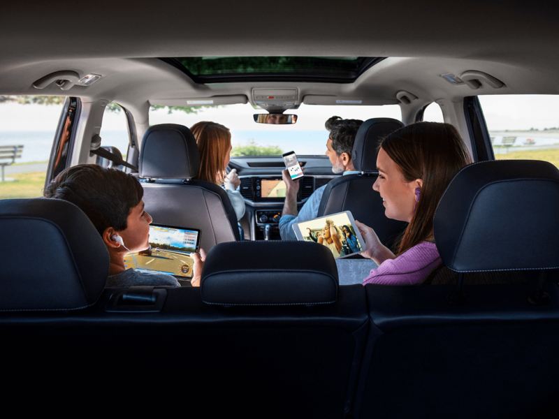 Una familia de cuatro personas activa el punto de acceso Car-Net para usar sus dispositivos portátiles mientras están estacionados en la costa.