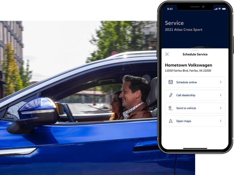 A man is driving his VW, the MyVW app is displayed on a superimposed mobile phone.