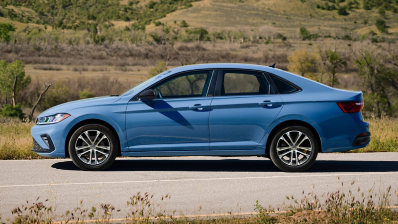 Profile view of a Jetta shown in Monterey Blue Pearl parked with wooded hills in the background.