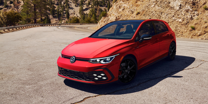 Golf GTI shown in Kings Red Metallic parked with mountains in the background.