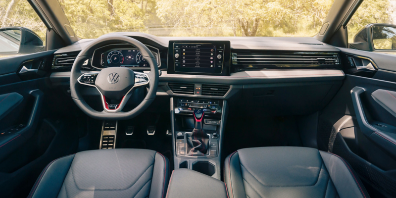 Vista interior de un Jetta GLI mostrando el volante, la pantalla de infoentretenimiento y el salpicadero.