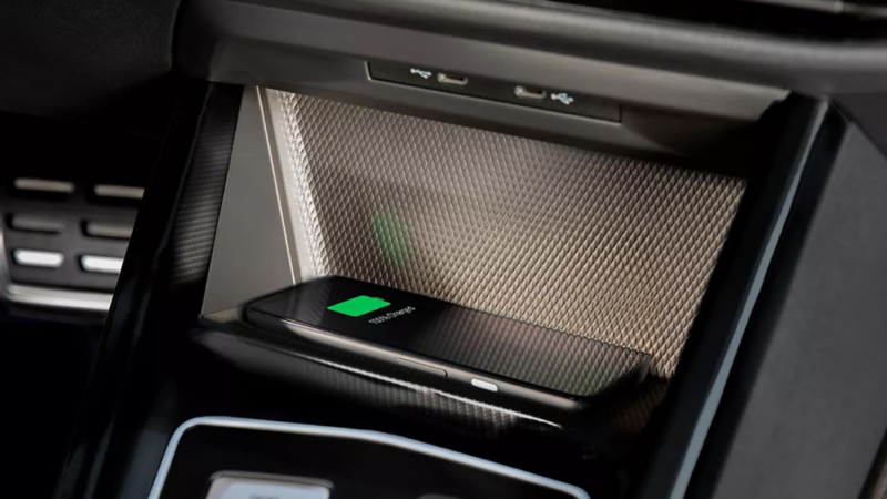A compatible cell phone charges using a wireless charging pad in a Volkswagen.