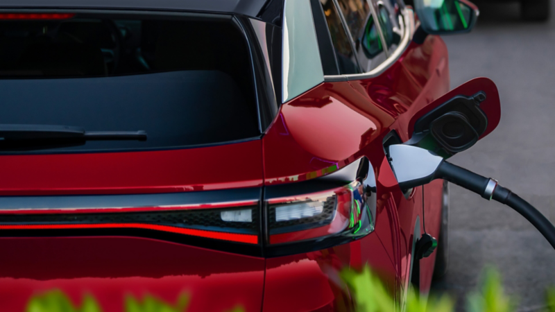 Side view of an ID.4 shown in Aurora Red Metallic parked at a indoor charging facility.