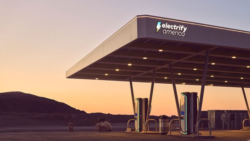 Electrify America charging station at sunset with desert mountains in the background.