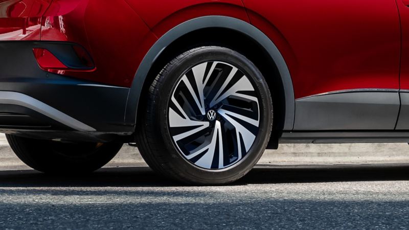 Primer plano de las ruedas de aleación de 21 pulgadas disponibles en un SUV ID.4 estacionado en color Aurora Red Metallic.