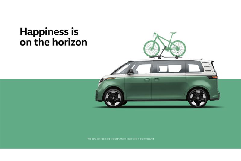 A side view of the ID. Buzz in Mahi Green Metallic with a bike attached to the roof rack in front of a two-tone white and green background with the words “Happiness is on the horizon” to the left of the vehicle.