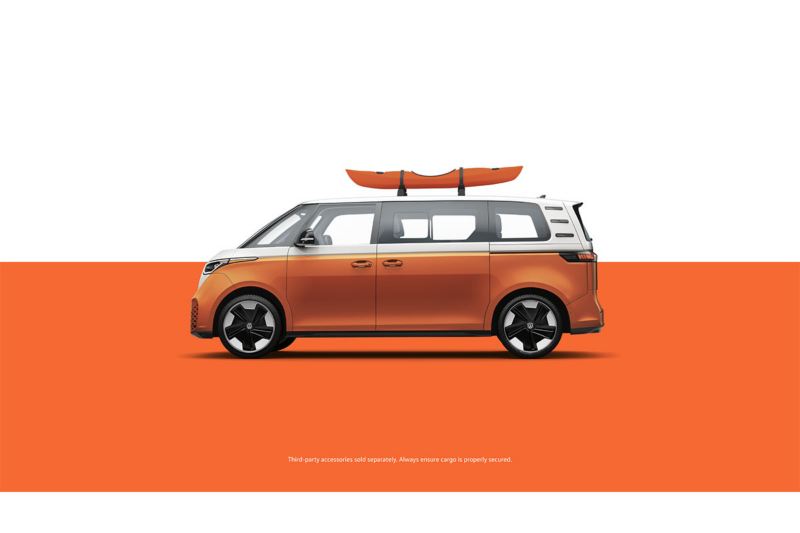 A side view of the ID. Buzz in Energetic Orange Metallic with a kayak attached to the roof rack in front of a two-tone white and orange background.