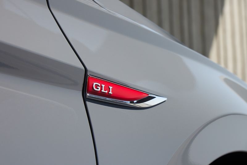 Toma de primer plano del distintivo de GLI rojo en el guardabarros del lado del pasajero de un Jetta GLI en color Pure Gray.
