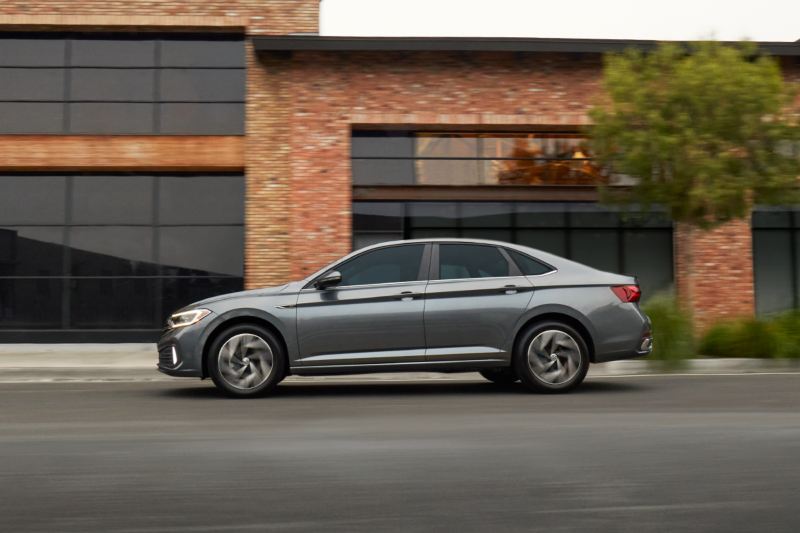 Jetta shown in Platinum Gray Metallic as seen from the front driving on a modern city street.