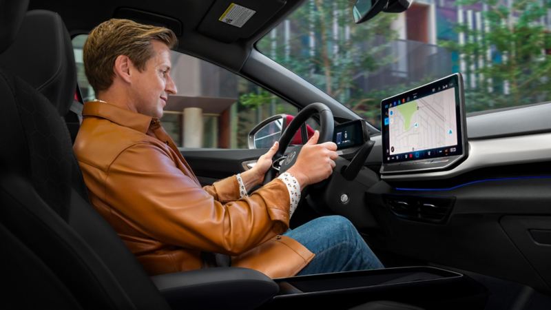Vista interior de un hombre en el asiento del conductor de un SUV ID.4 con su atención centrada en la pantalla de la consola central al arrancar.