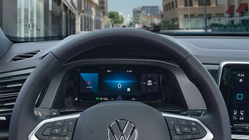 Interior view of an Atlas Cross Sport showing the steering wheel and head-up display information on the windshield.