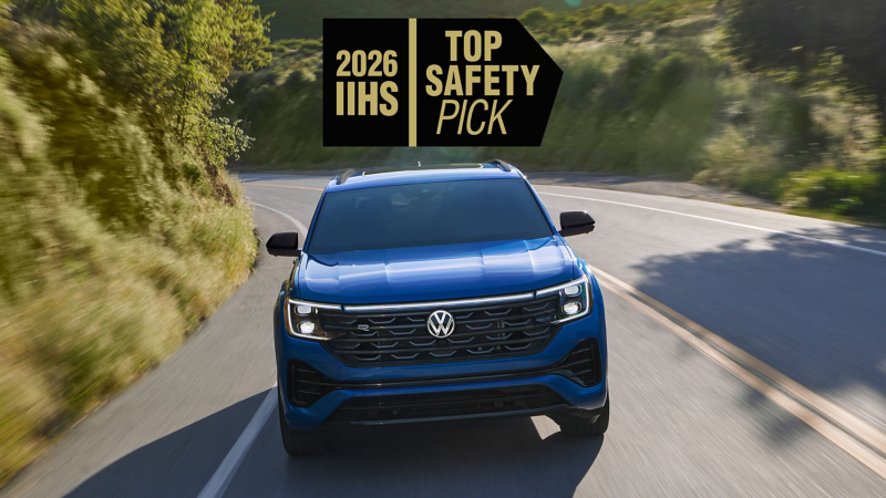 A front view of an Atlas Cross Sport shown in Mountain Lake Blue driving on a wooded mountain road with a safety rating icon overlayed at the top of the image.