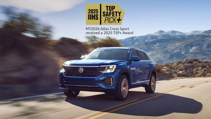 A front view of an Atlas Cross Sport shown in Mountain Lake Blue driving on a wooded mountain road with a safety rating icon overlayed at the top of the image.