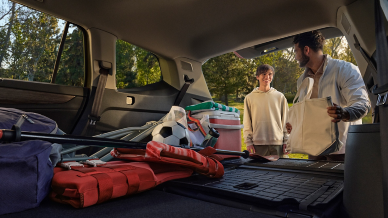 A father and son load sports equipment into the cargo area of an Atlas.