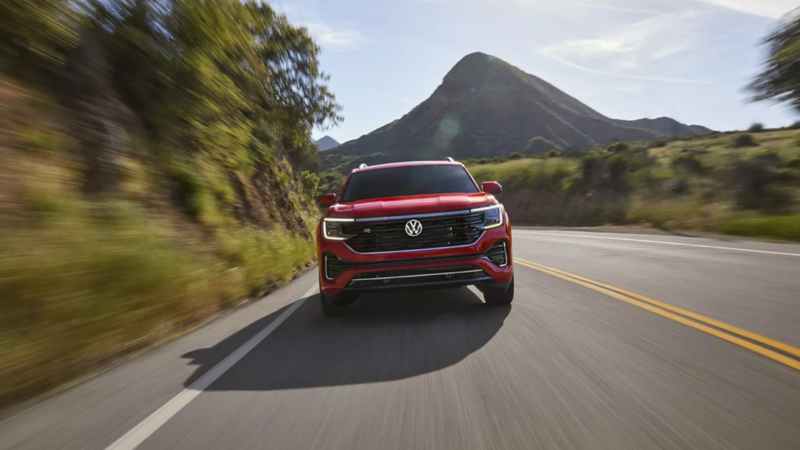 Atlas shown in Aurora Red Metallic seen from the front as it drives on a mountain road.