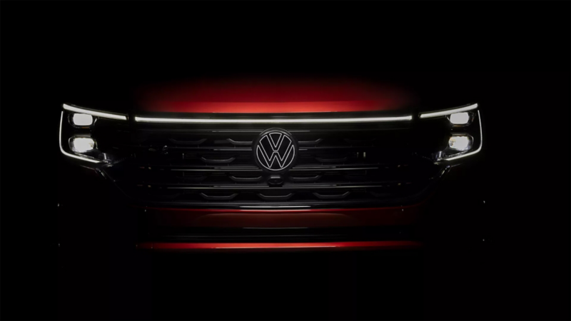 Front of an Atlas in Aurora Red Metallic at night with available illuminated grille and front VW emblem.