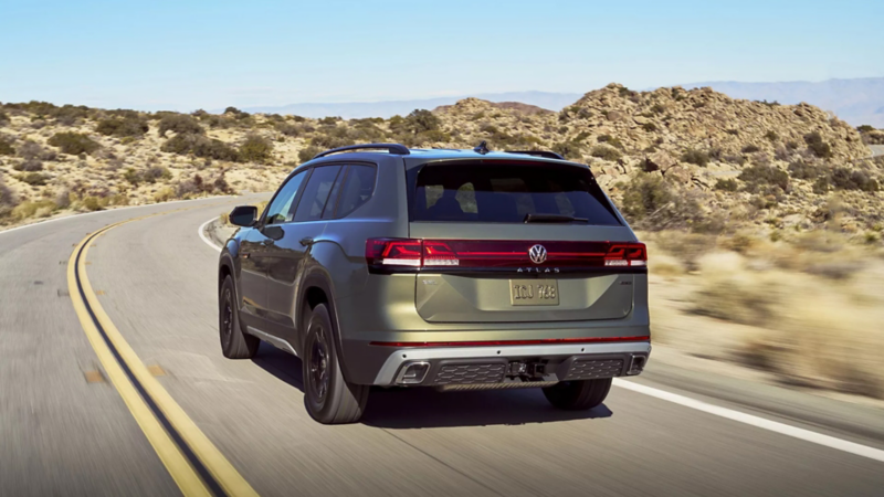 Rear view of an Atlas shown in Avocado Green Metallic driving on a highway through the desert.