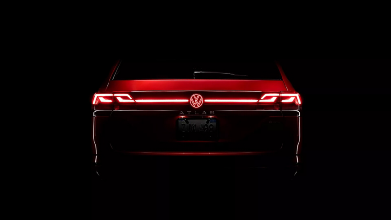 Rear of an Atlas in Aurora Red Metallic at night with available illuminated grille and rear VW emblem.