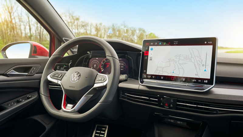 Interior view of the Kings Red Metallic Golf GTI Autobahn showing the steering wheel, fully digital gauge cluster, touchscreen display available navigation map and available head-up display