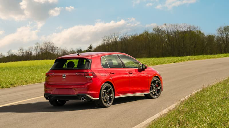 Back three-quarter view of the 2025 Volkswagen Golf GTI in Kings Red Metallic parked on a open road.