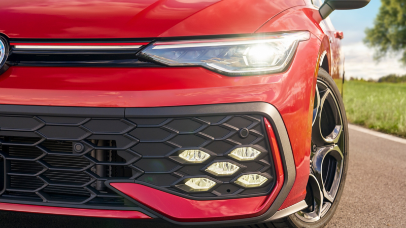 Primer plano de la parrilla delantera y el faro del Golf GTI Autobahn en Kings Red Metallic.