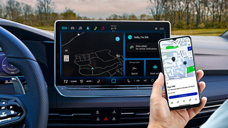 Interior of a Volkswagen Golf R featuring a front passenger holding a smartphone in front of the central touchscreen display.