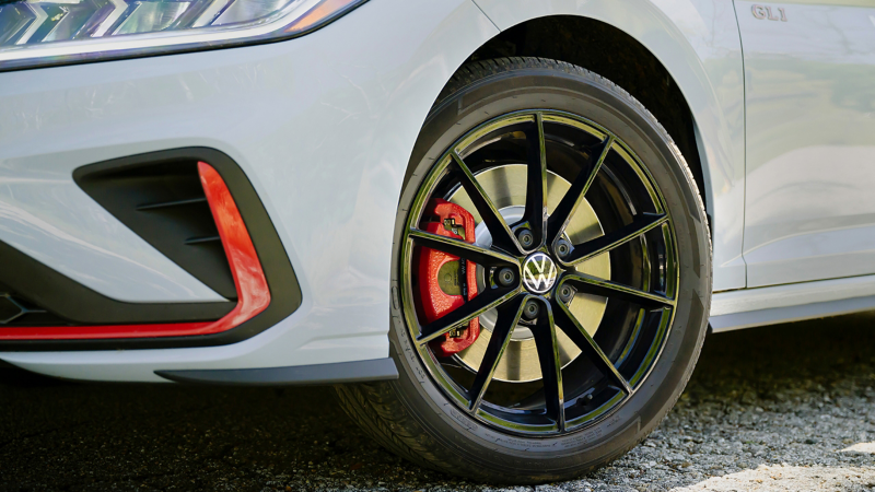 Close-up image of the available 18" black alloy wheels on the Jetta GLI shown in Monument Gray
